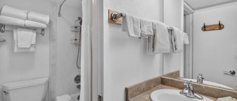 A bathroom with a toilet, shower, and sink.