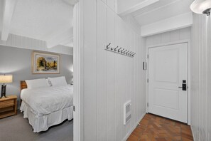 Un dormitorio con cama, mesita de noche, lámpara, un cuadro en la pared y una puerta con un letrero encima.