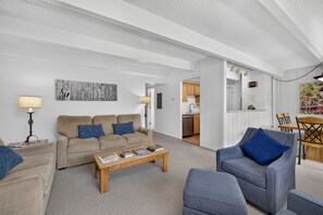 Una sala de estar con sofá, sillones, una mesa de centro y un comedor con mesa y sillas.