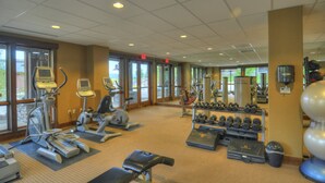 Academia com esteiras, elípticos, pesos livres e bolas de exercício.