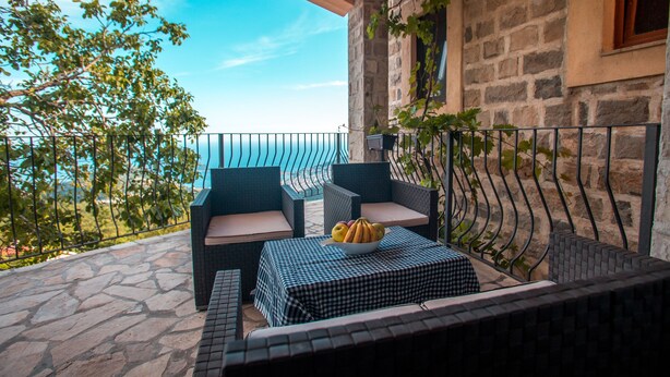 A balcony with wicker furniture, a checkered table, and a bowl of fruit. - 3BR Villa w Amazing Hilltop View on Budva Riviera (Lapčići)