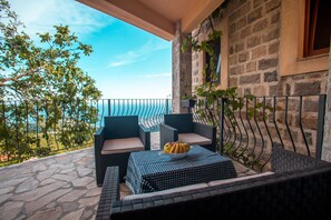A balcony with wicker furniture, a checkered table, and a bowl of fruit.