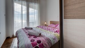 A bedroom with a bed, white curtains, a nightstand with a lamp, and a wooden floor. - 3BR Villa w Amazing Hilltop View on Budva Riviera (Lapčići)