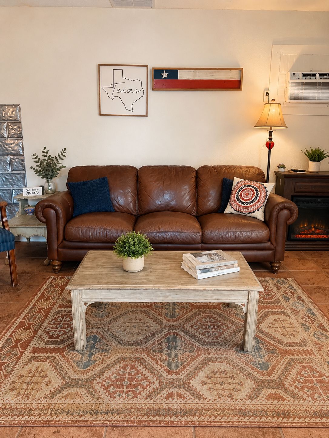 Ein Wohnzimmer mit einem braunen Ledersofa, einem Holztisch, einem gemusterten Teppich, einer Texas-Flagge und einer gerahmten Karte von Texas.