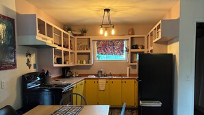 Una cocina con una mesa de comedor, sillas, un refrigerador y armarios.