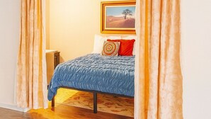 Een slaapkamer met een bed, een schilderij aan de muur en gordijnen.