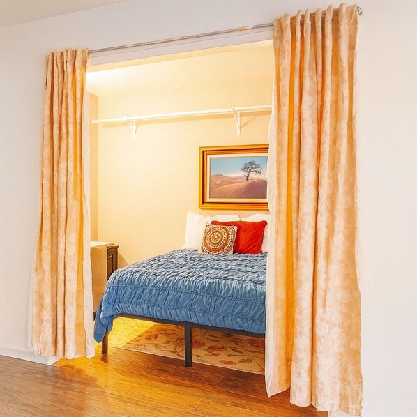 Une chambre à coucher avec un lit, un tableau au mur et des rideaux.
