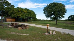 A rustic barn with a gravel path leading to it, surrounded by trees and a clear sky. - Unique,Eclectic, Scenic Farm, Relax in the jacuzzi tub,Nature Inspired (Saint Jo)