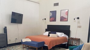 A bedroom with a bed, bedside tables, a TV, and artwork on the wall.