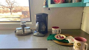 A kitchen counter with a coffee maker, jars, a mug, and a plate with food. - Unique,Eclectic, Scenic Farm, Relax in the jacuzzi tub,Nature Inspired (Saint Jo)