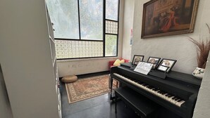 A room with a piano, a rug, a window with a view, and a painting on the wall. - Unique,Eclectic, Scenic Farm, Relax in the jacuzzi tub,Nature Inspired (Saint Jo)