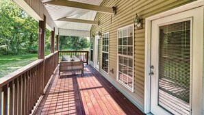 A covered porch with a bench, a door with a window, and a view of a green landscape. - Smoky Mountain Chalet | Pool | Steps to Parkway (Pigeon Forge)