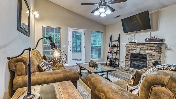A living room with a fireplace, sofa, coffee table, and a ceiling fan. - Smoky Mountain Chalet | Pool | Steps to Parkway (Pigeon Forge)