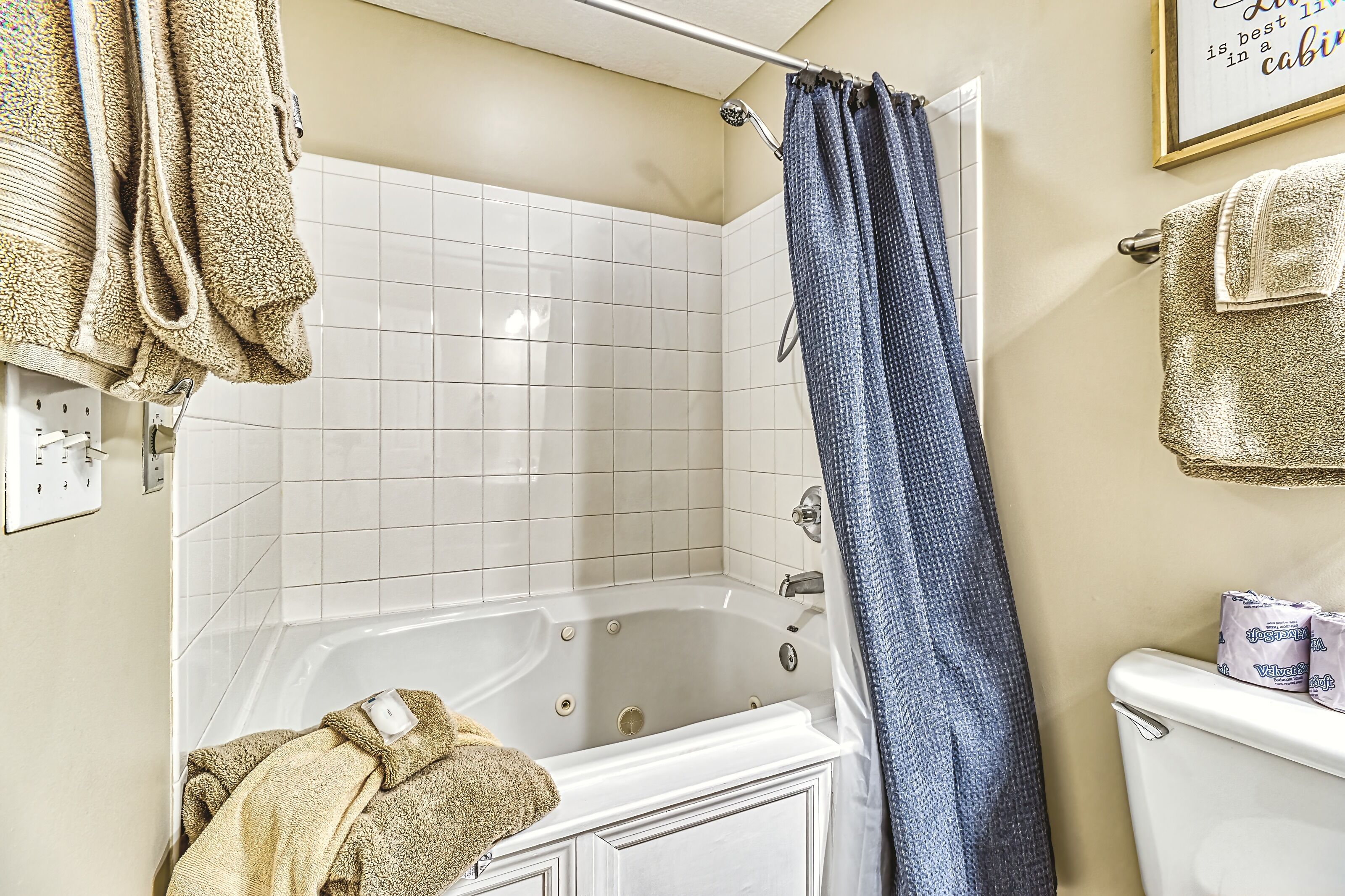 A bathroom with a bathtub, a shower curtain, and a toilet.