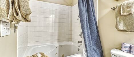A bathroom with a bathtub, a shower curtain, and a toilet.