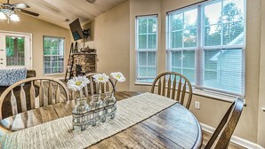 A dining area with a wooden table, chairs, and a vase with flowers. - Smoky Mountain Chalet | Pool | Steps to Parkway (Pigeon Forge)