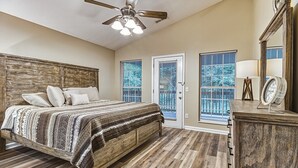 A bedroom with a wooden bed, a ceiling fan, a dresser, and a large window. - Smoky Mountain Chalet | Pool | Steps to Parkway (Pigeon Forge)