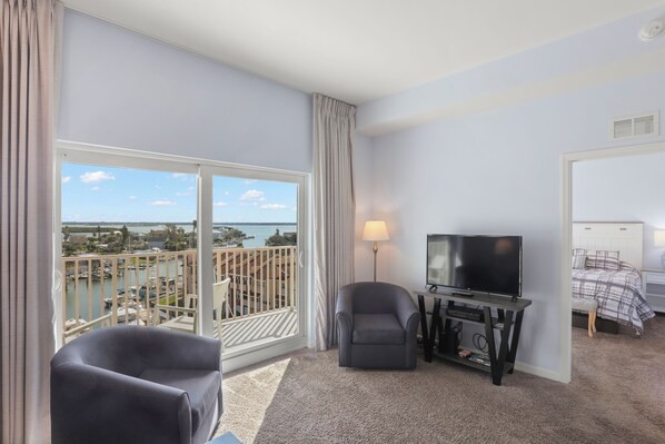 A hotel room with a balcony, a TV, a chair, and a bed.