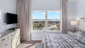 A hotel room with a bed, a TV, a window with a view of a marina, and a lamp on the nightstand. - 🌴 Madeira Bay Resort I #1707 – Clean, Comfortable & Just Steps from the Beach (Madeira Beach)
