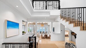 A spacious interior with a high ceiling, a staircase with black railings, and a view to the outside. - Oceanfront, Private Dock, Paddle Boards, Feb Pt Access!! (Georgetown, BS)