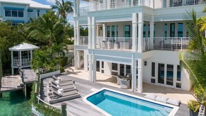 A multi-story resort with a pool, outdoor seating, and a dock. - Oceanfront, Private Dock, Paddle Boards, Feb Pt Access!! (Georgetown, BS)