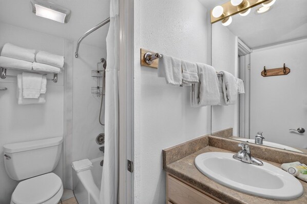 A bathroom with a toilet, shower, and sink.