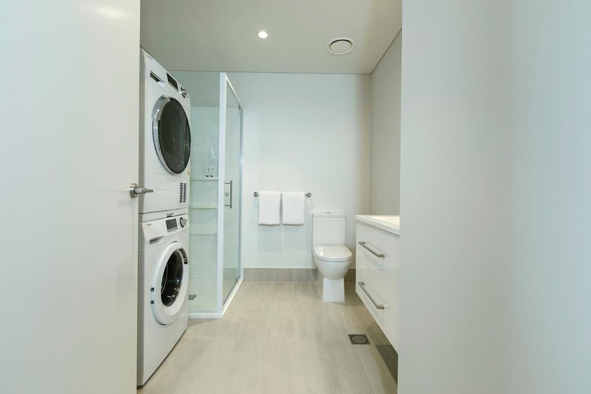 Un baño moderno con lavadora incorporada, inodoro y cabina de ducha.