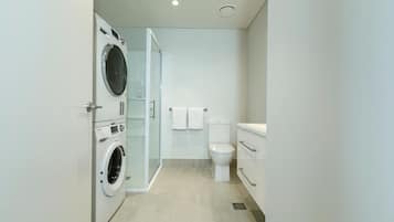 Un baño moderno con lavadora incorporada, inodoro y cabina de ducha.