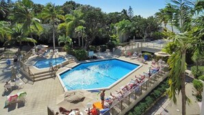A pool area with multiple pools, lounge chairs, and palm trees. - Top floor condo in Key Largo with spectacular Sunset views (Key Largo)