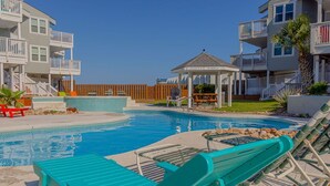 A pool area with lounge chairs, a gazebo, and a wooden fence. - ⭐⭐⭐⭐⭐ BEAUTIFUL OCEAN VIEWS + Huge Deck + Heated Pool + Hot tub + Boardwalk  (Port Aransas)