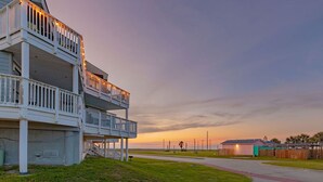 A multi-story building with balconies, a grassy area, and a road in the background. - ⭐⭐⭐⭐⭐ BEAUTIFUL OCEAN VIEWS + Huge Deck + Heated Pool + Hot tub + Boardwalk  (Port Aransas)