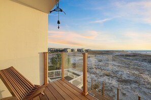 A wooden deck with a bench overlooking a beach.