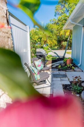 Eine Terrasse mit Gartenmöbeln, einem Grill und einem Gartenbereich.