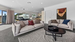 Ein modernes Wohnzimmer mit zwei Sofas, einem Couchtisch und einem großen Fenster mit Blick ins Freie.