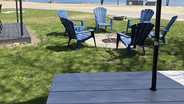 A picnic setup with a table and chairs, a tent, and a view of a lake.