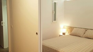 Ein Schlafzimmer mit einem Bett, einem Nachttisch mit Lampe und einer Tür.