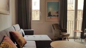 Ein Wohnzimmer mit einer Couch, Sesseln, einem kleinen Tisch und Blick ins Freie.