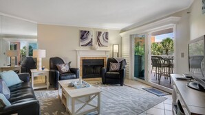 Una sala de estar con chimenea, dos sillones de cuero negro, un sofá, una mesa de centro y un televisor.