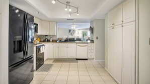 Una cocina moderna con armarios blancos, un refrigerador negro y una lámpara en el techo.