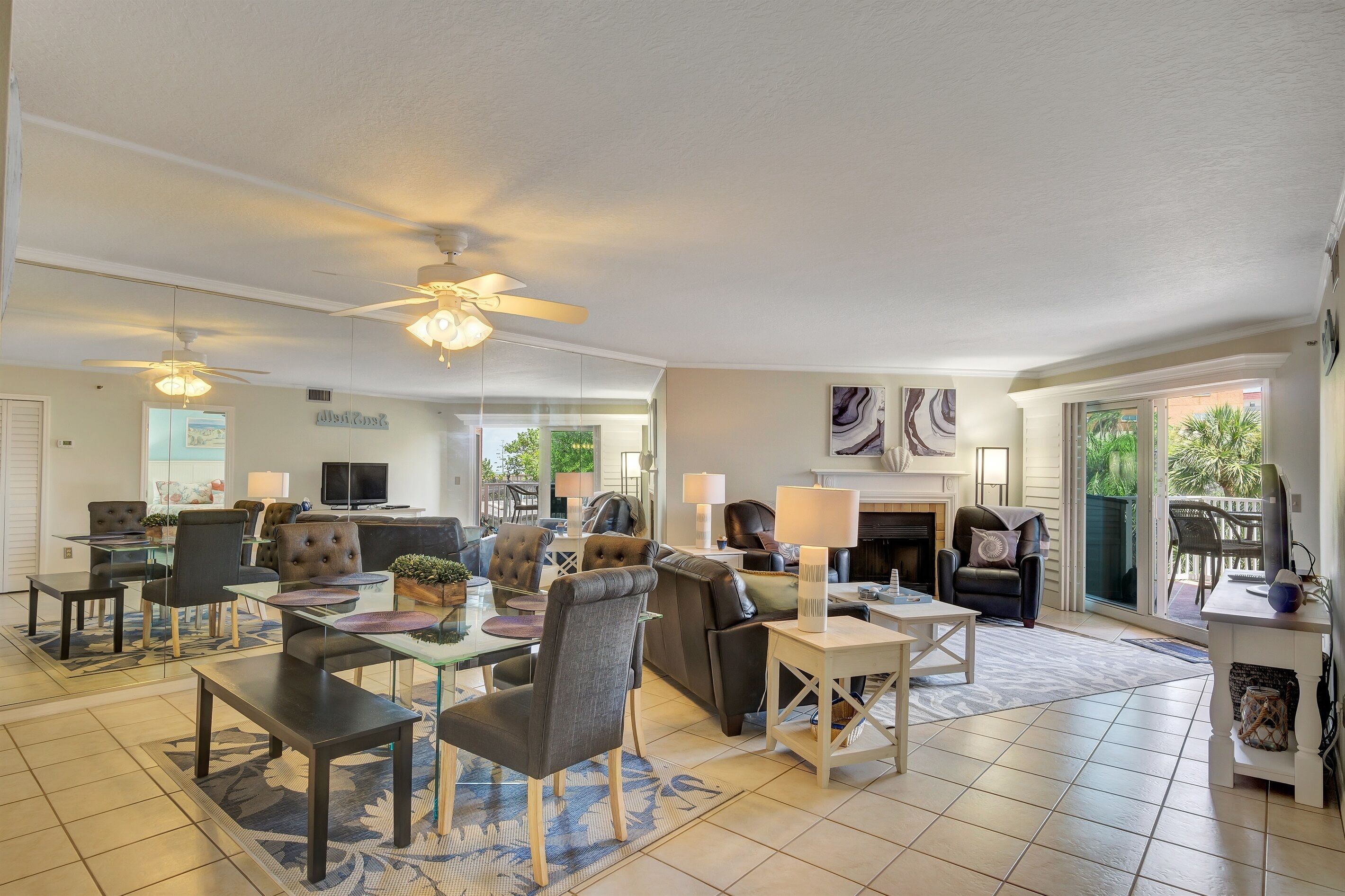 A spacious living area with a dining table, comfortable seating, a fireplace, and large windows offering a view of the outdoors.