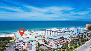 Un hotel con varias edificaciones, estacionamiento y una playa al fondo.