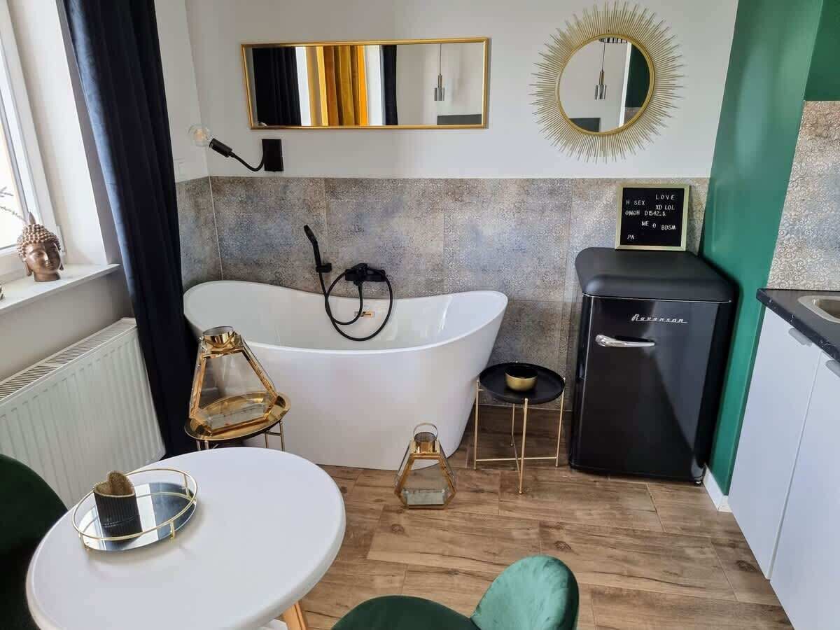 Une salle de bain moderne avec une baignoire sur pieds, un meuble-lavabo avec un miroir et un petit réfrigérateur.