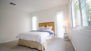 A bedroom with a bed, a bedside table with a lamp, and a window. - FREE NIGHT. Pay for 2 stay for 3 (Mollymook Beach)