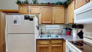 Une cuisine avec des meubles de rangement en bois, un réfrigérateur, un évier et une cuisinière.