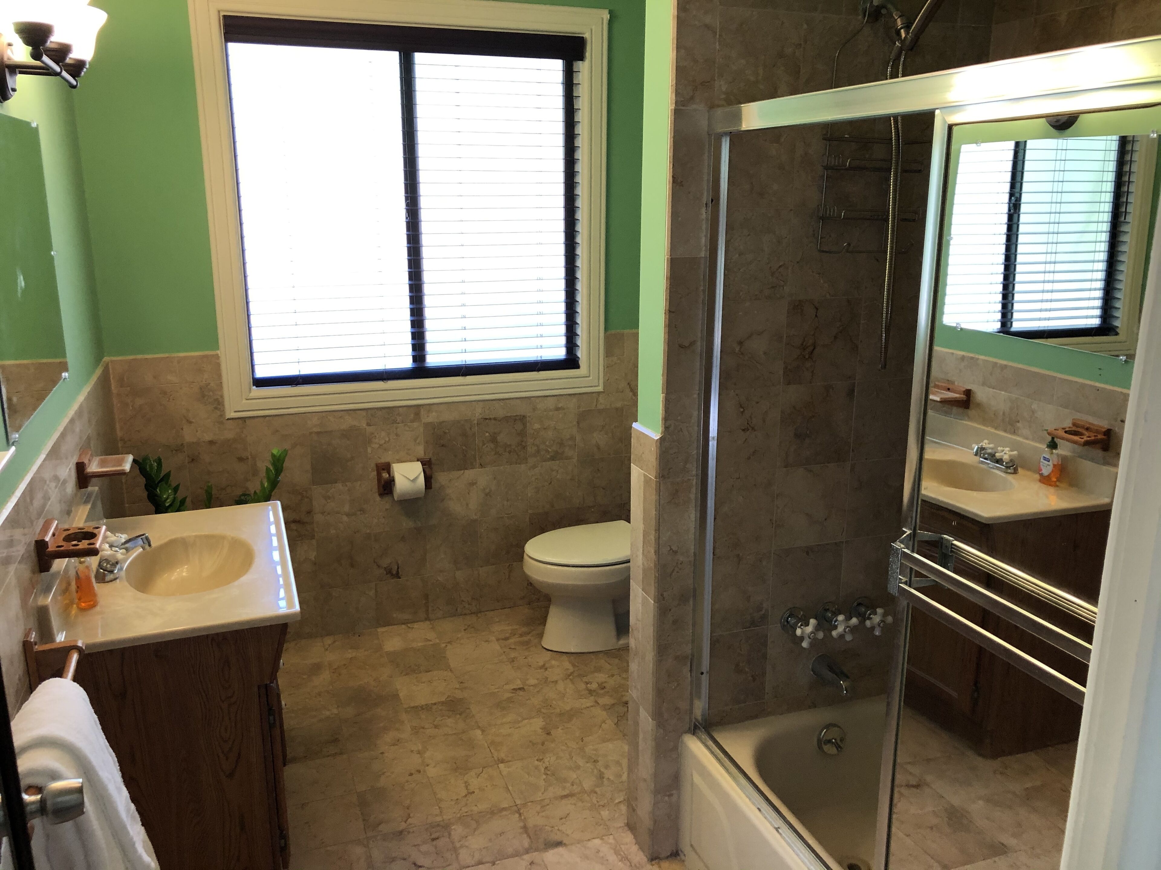 Een badkamer met een douchecabine van glas, een wastafel en een toilet.