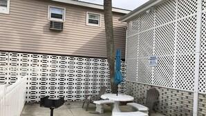 Un'area patio con un recinto bianco a griglia, una cassetta postale, un ombrello blu e mobili da esterno.