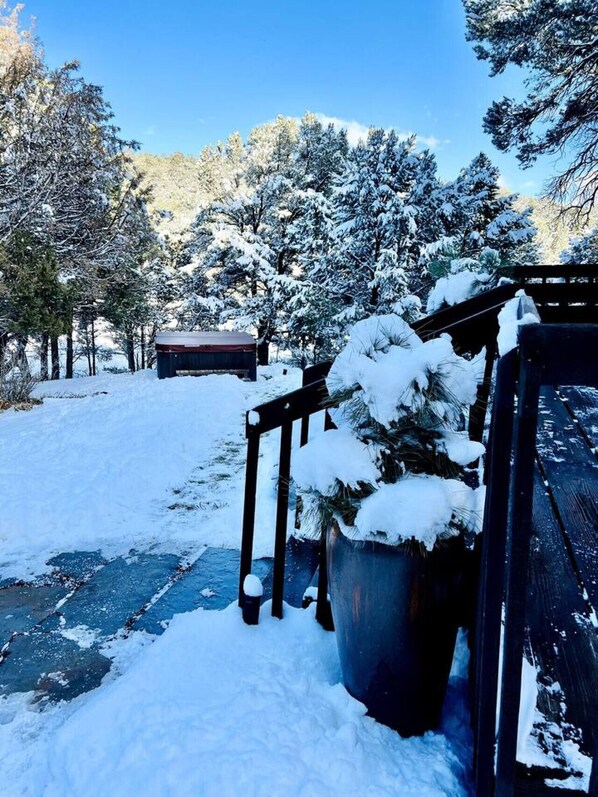 A snow-covered outdoor area with a wooden structure and a large planter filled with snow.