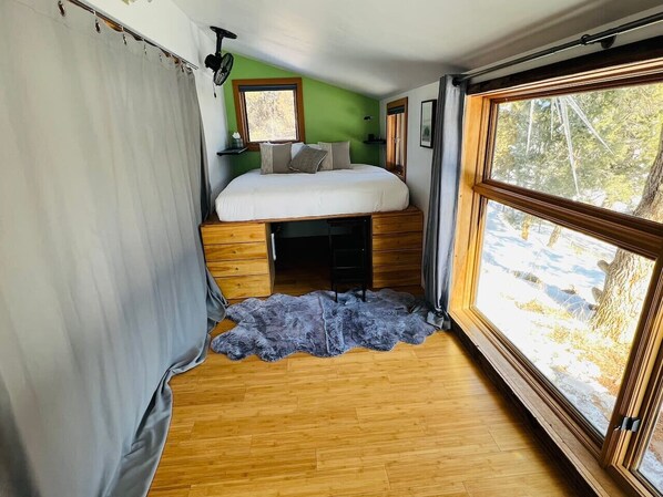 Un dormitorio pequeño con una cama, un ventanal y una alfombra de piel.