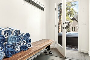 A bench with rolled towels, a coat rack, and a door leading outside.