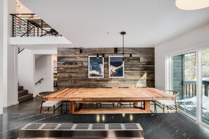A modern dining area with a wooden table and chairs, a black marble floor, and a staircase with a metal railing. - 5 King Beds+6 Bunks. Winter Bus. Close to town. (Breckenridge)